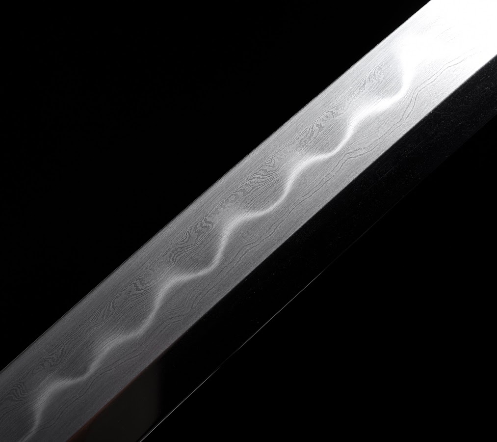 Close view of layered pattern-welded steel and a wavy hardened boundary